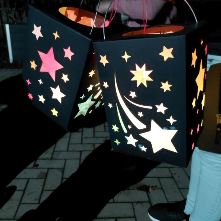 Zwei Laternen mit Sternen drauf leuchten im dunklen.