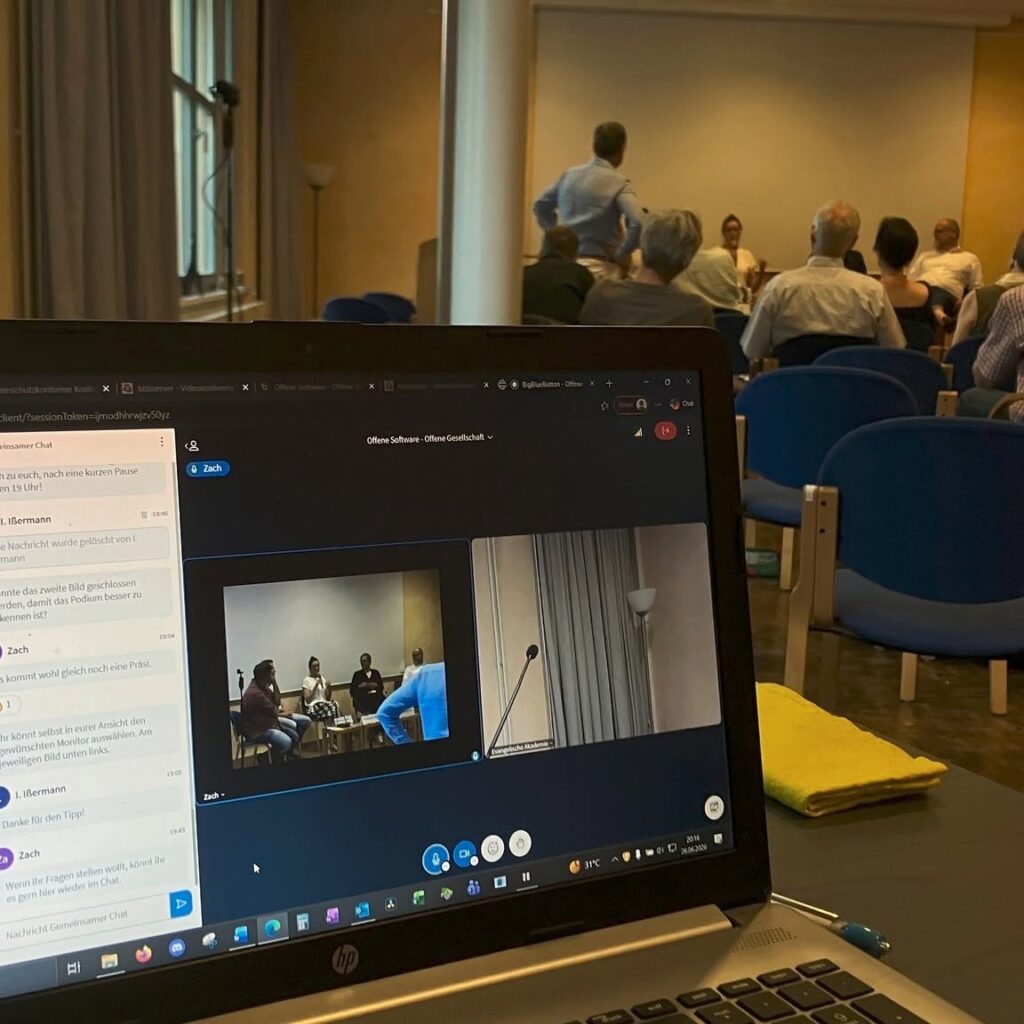 Aufnahme der Diskussionsrunde auf einem Laptop, dessen Monitor sichtbar ist